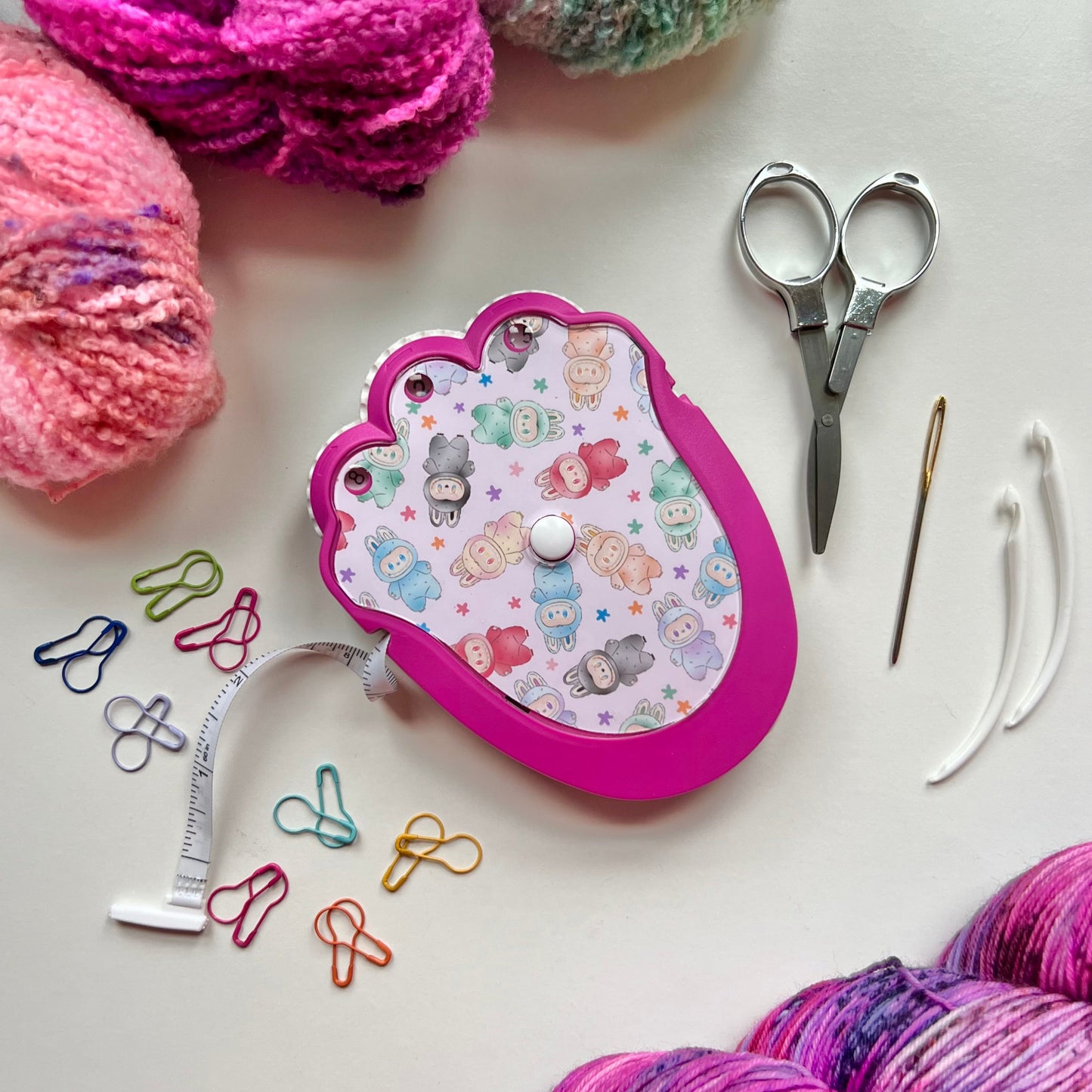 Yarn, scissors, measuring tape, and crochet hook on a white surface