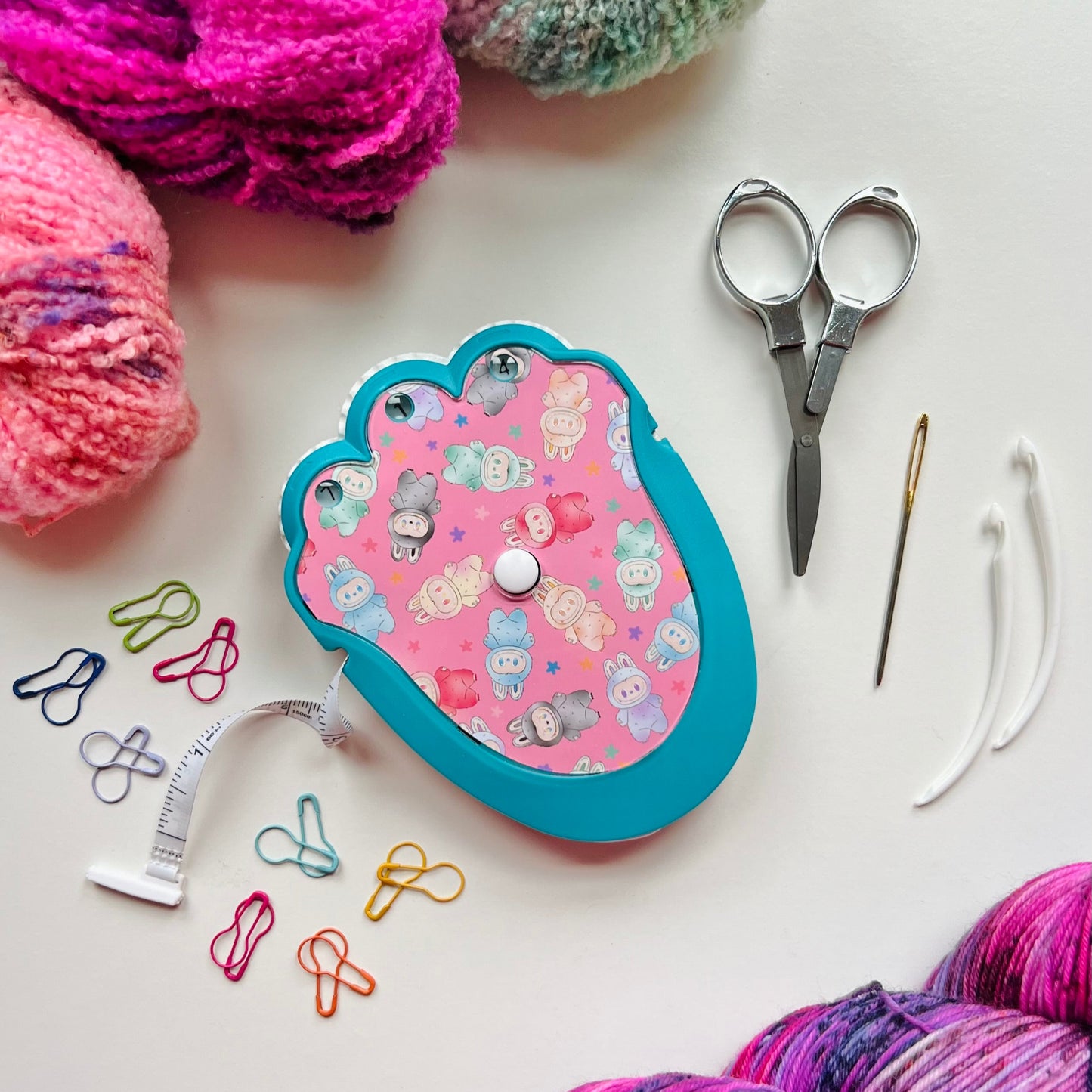Yarn, scissors, and knitting tools on a white surface