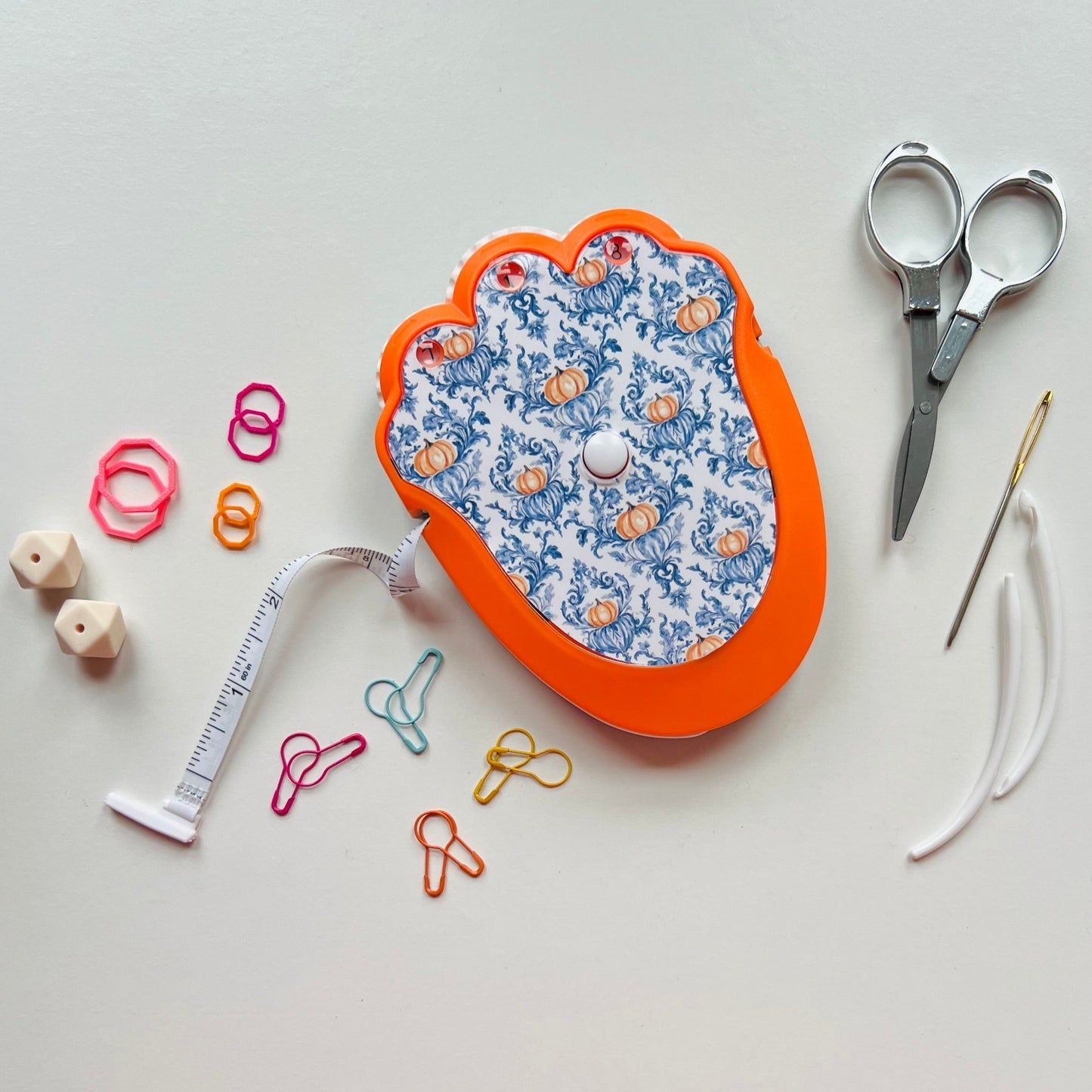 Knitting  kit with scissors, tape measure, and pins on a light background
