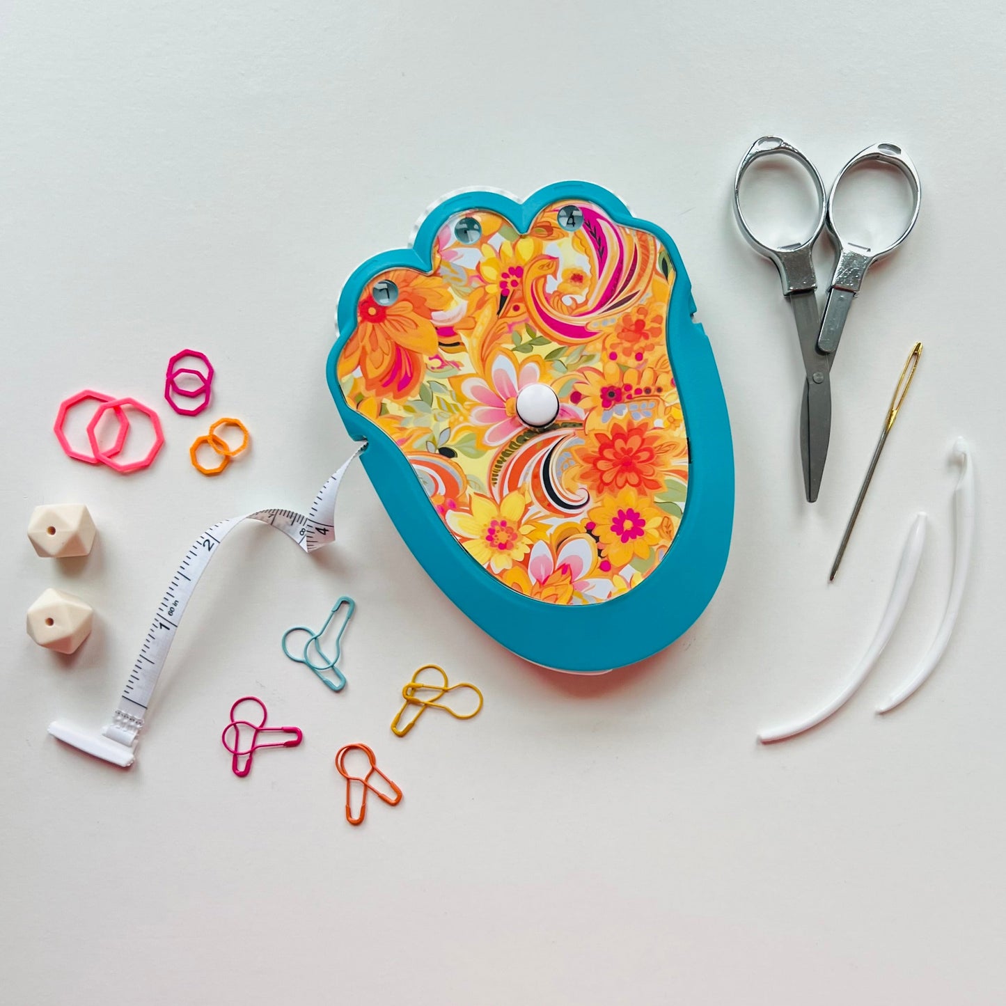 Colorful knitting kit with scissors, thread, and other supplies on a white background