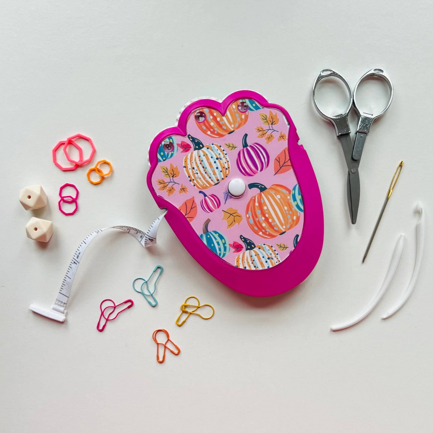 Pink knitting kit with colorful patterns on a white background