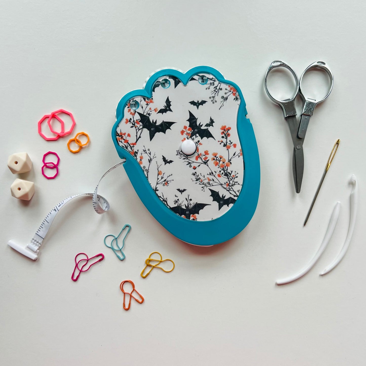 Knitting  kit with floral design, scissors, thread, and other sewing tools on a white background