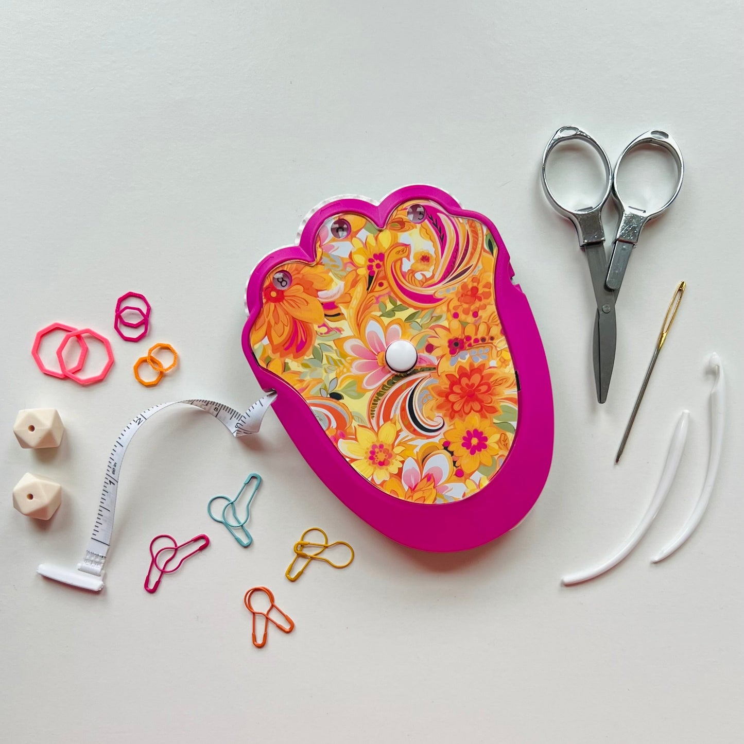 Decorative knitting kit with scissors, measuring tape, and other tools on a white background