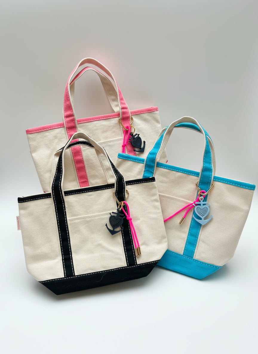 Three tote bags with colorful handles and keychains on a white background