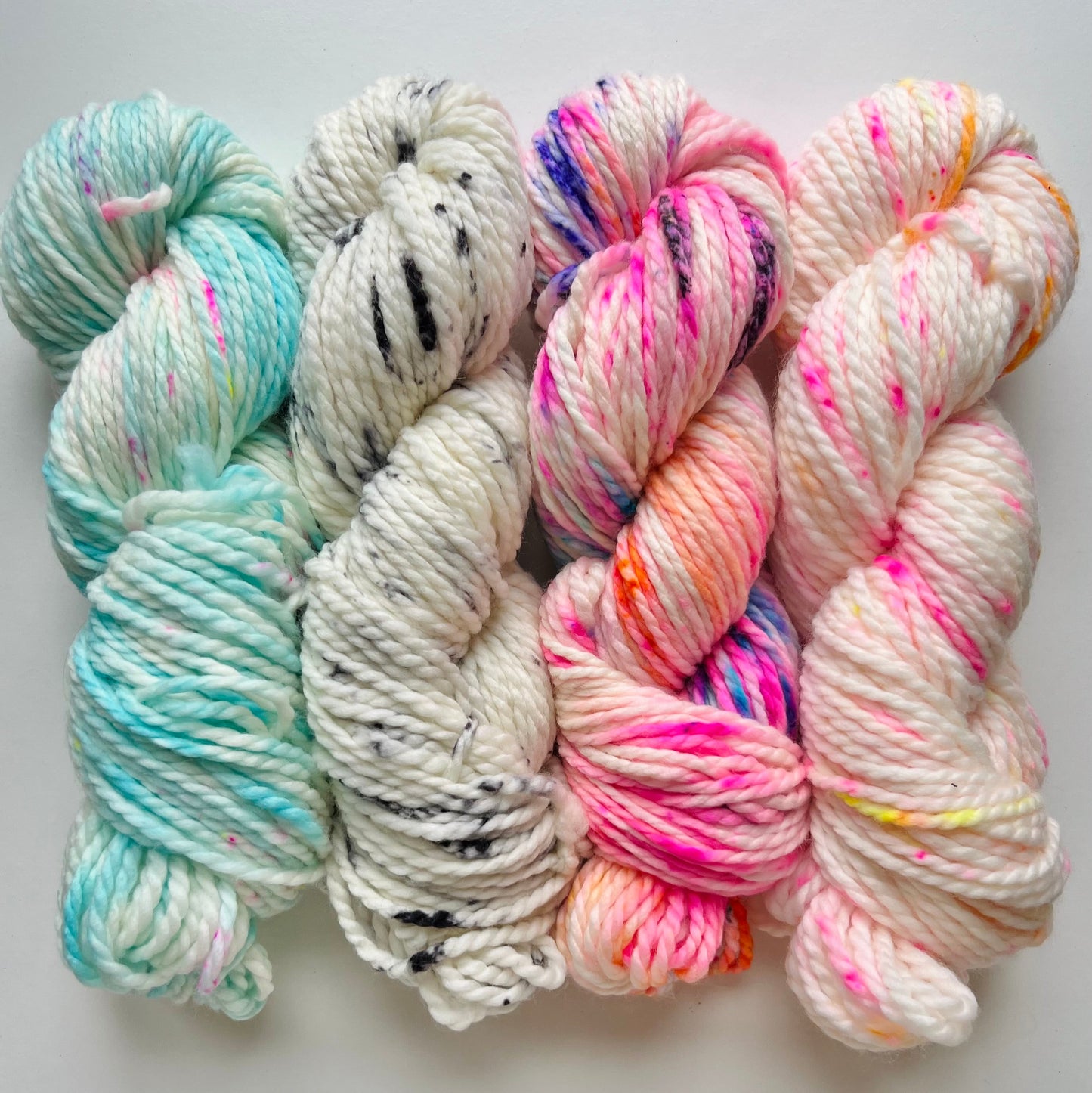 4 skeins of colorful yarn on a white background