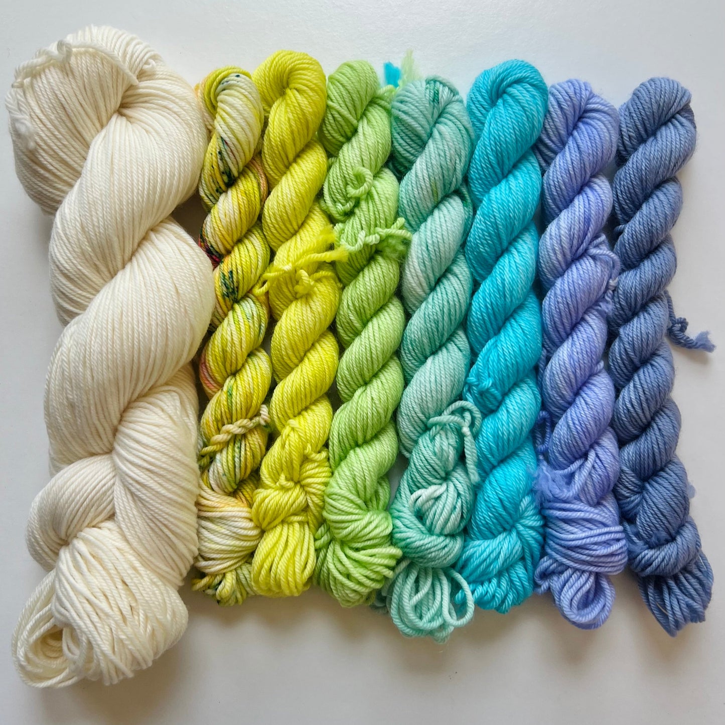 Set of yarn skeins in a rainbow gradient on a white background