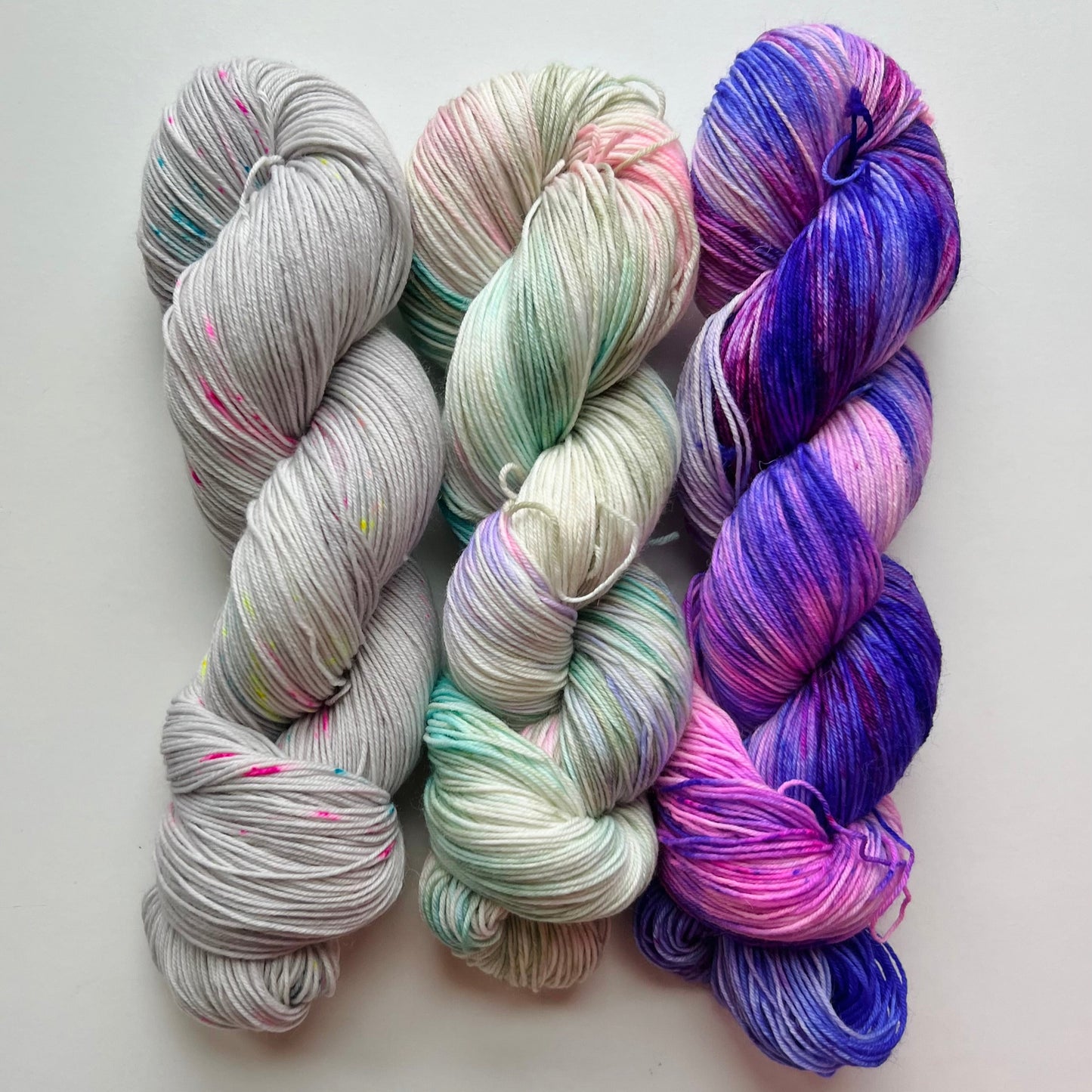 Three skeins of colorful yarn on a light background