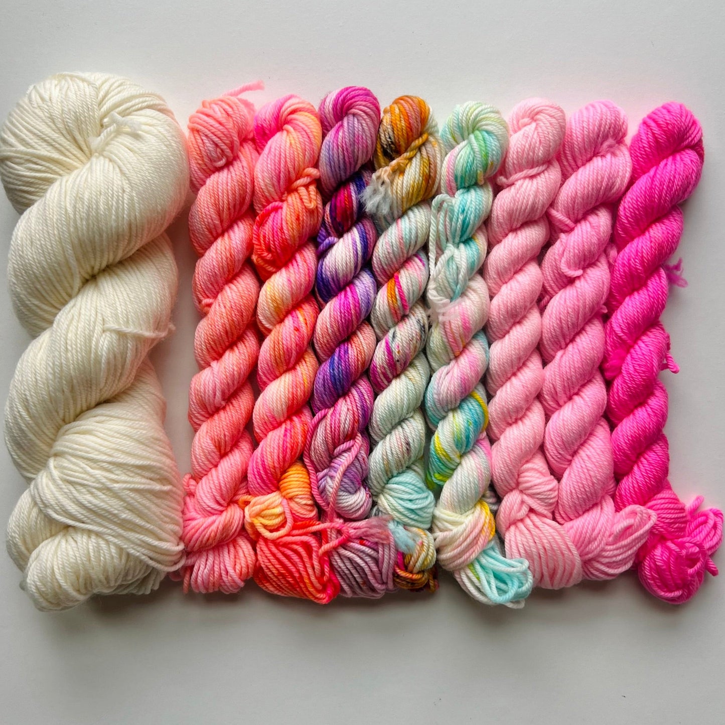 Collection of colorful yarn skeins on a light gray background