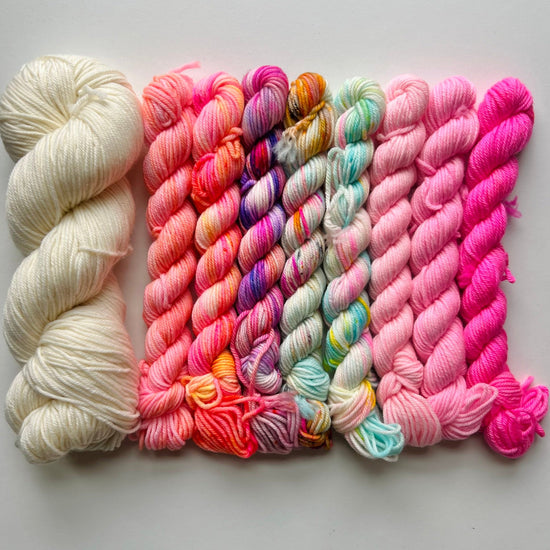 Collection of colorful yarn skeins on a light gray background