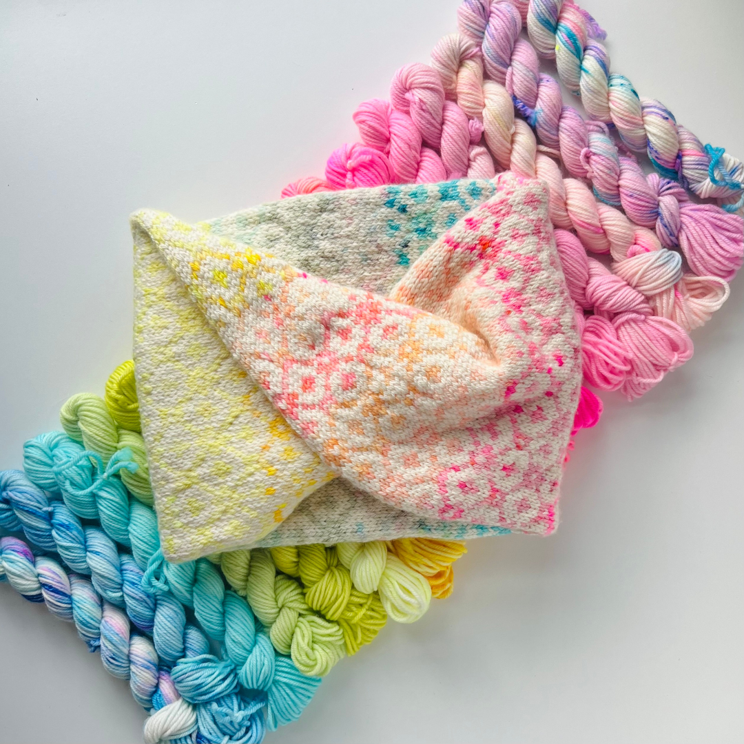 Colorful yarn skeins and a knitted item on a light gray background