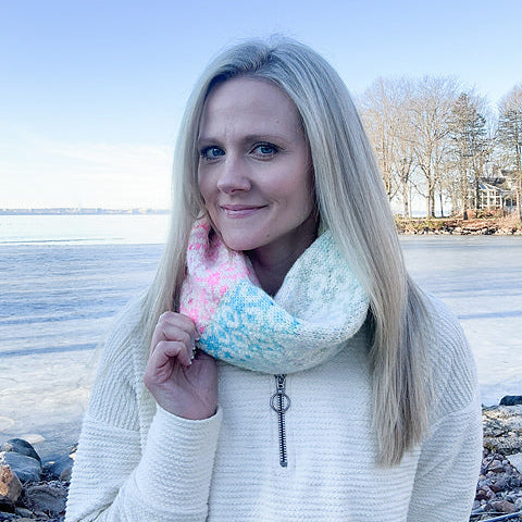 Woman wearing a colorful cowl by a frozen lake with trees in the background