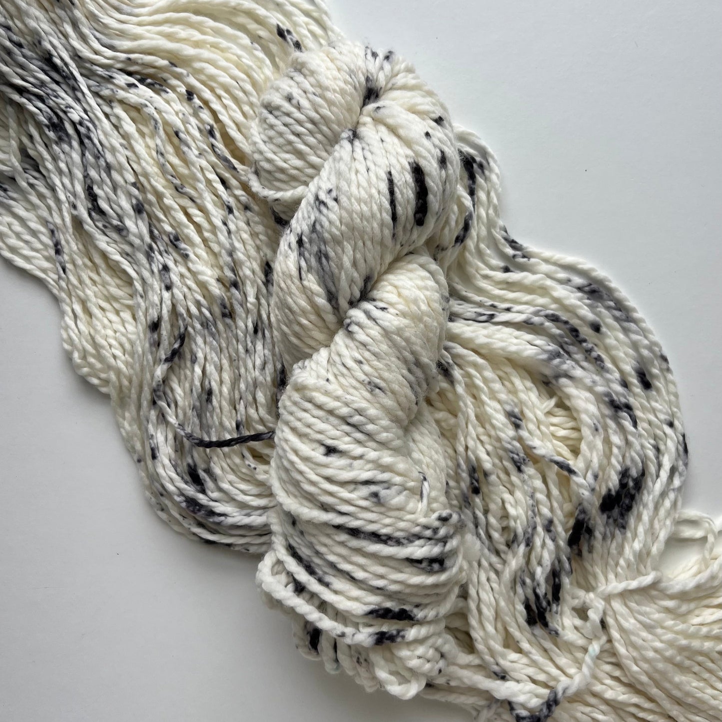 White yarn with black speckles on a light gray background