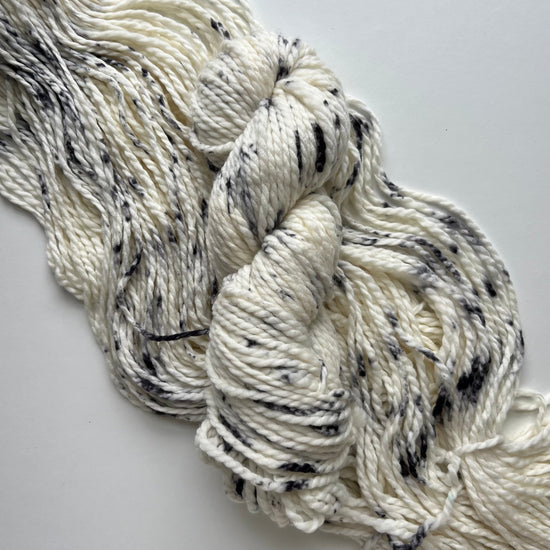 White yarn with black speckles on a light gray background