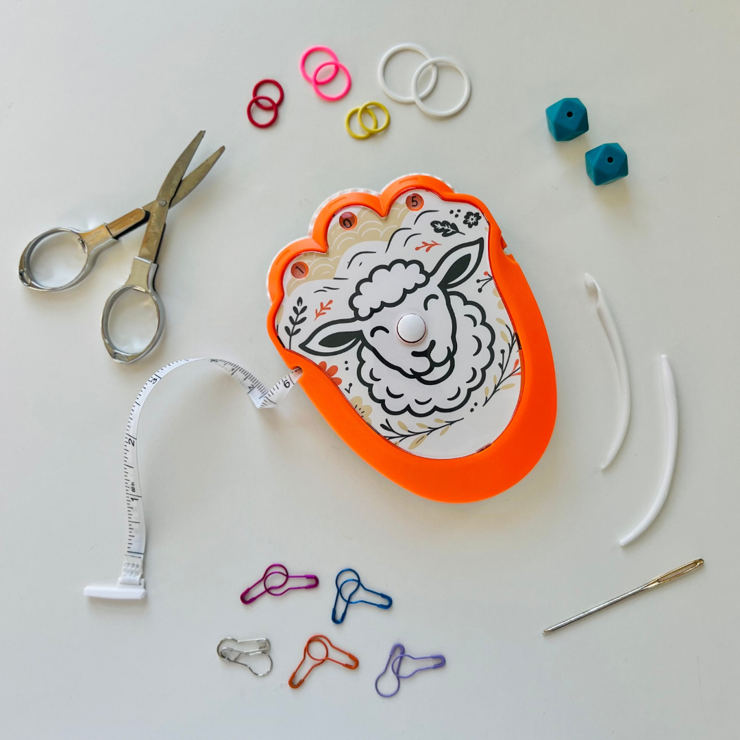 Crafting tools including scissors, measuring tape, and colorful rubber bands on a white surface.