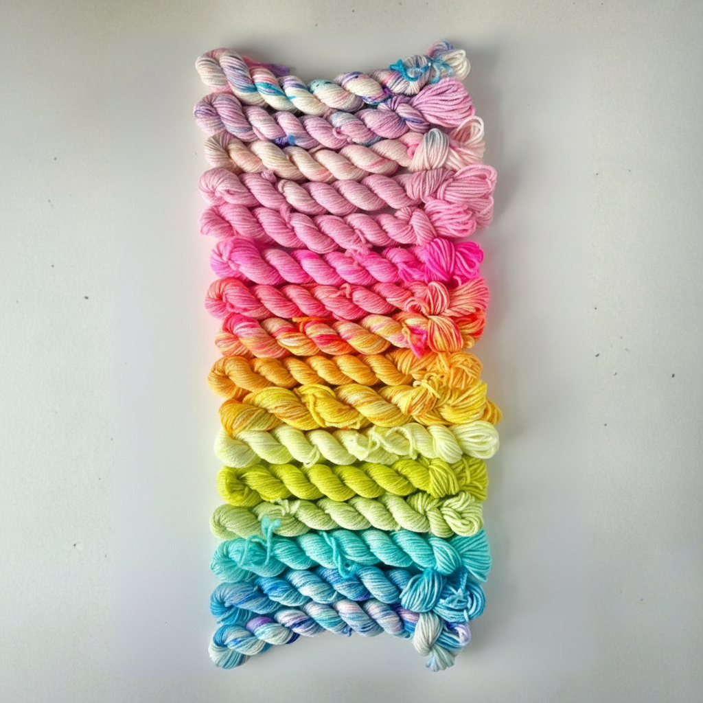 Multicolored yarn skeins arranged in a gradient on a light gray background