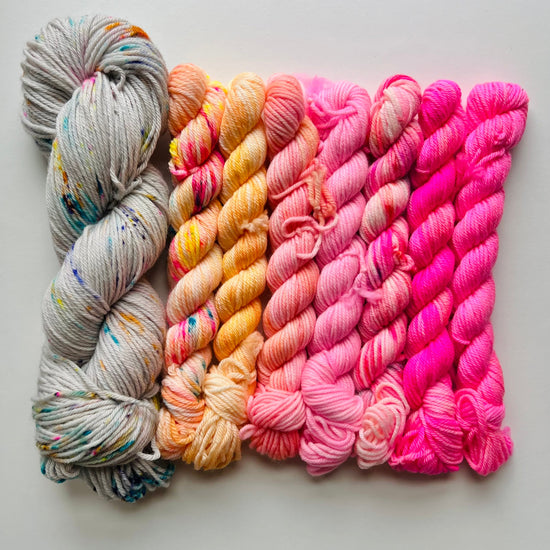 mini skeins of yarn in gray, orange, and pink on a light gray background