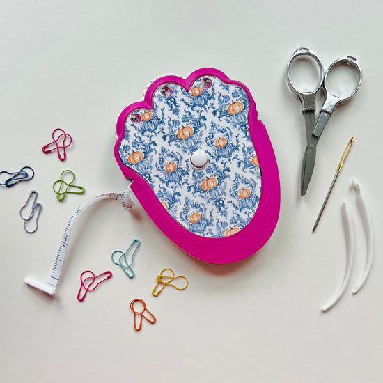 crochet kit with scissors, tape measure, and pins on a light background