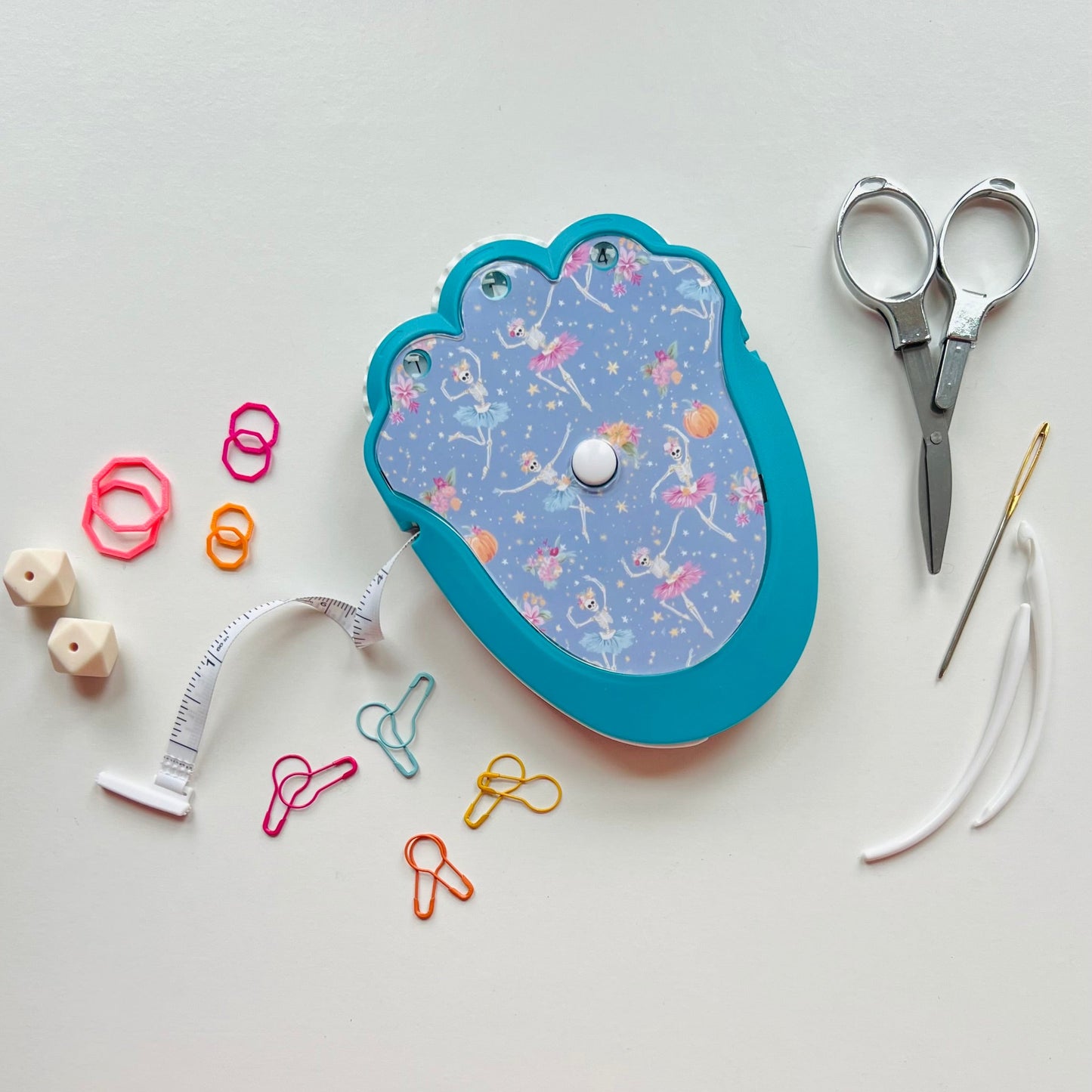 Decorative knitting kit with scissors, thread, and colorful accessories on a light gray background