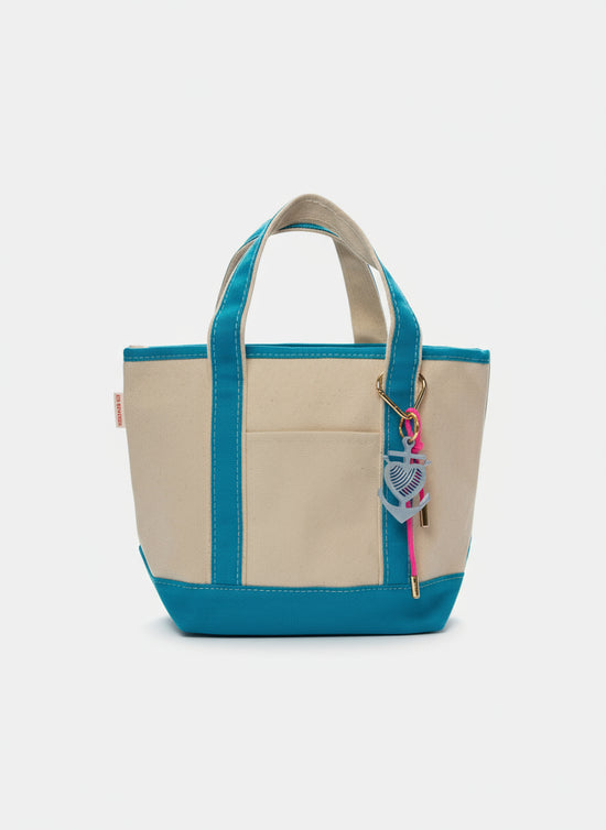 Beige and blue tote bag with a keychain on a white surface.