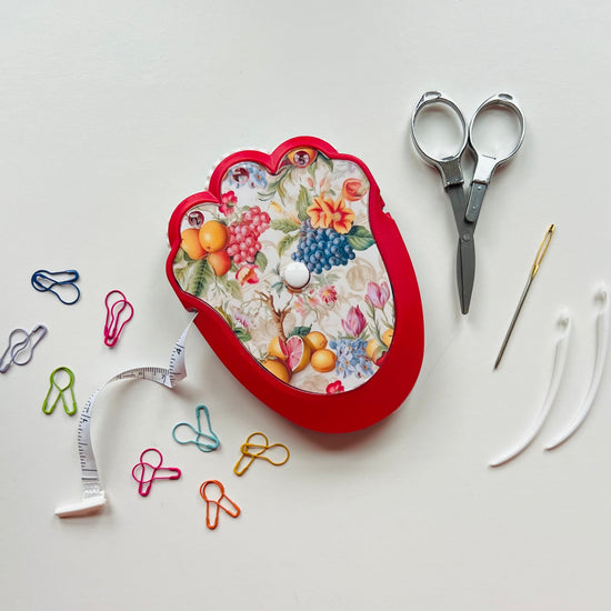 Decorative crocheting kit with scissors, pins, and a needle on a white background