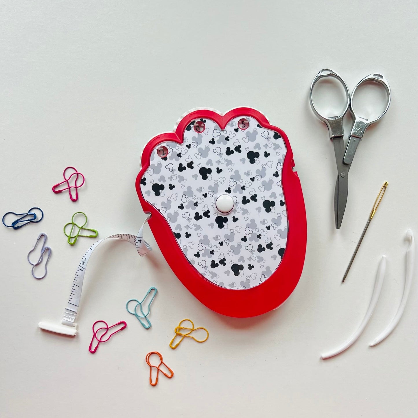 Crocheting tool kit with scissors, needle, and measuring tape on a white background