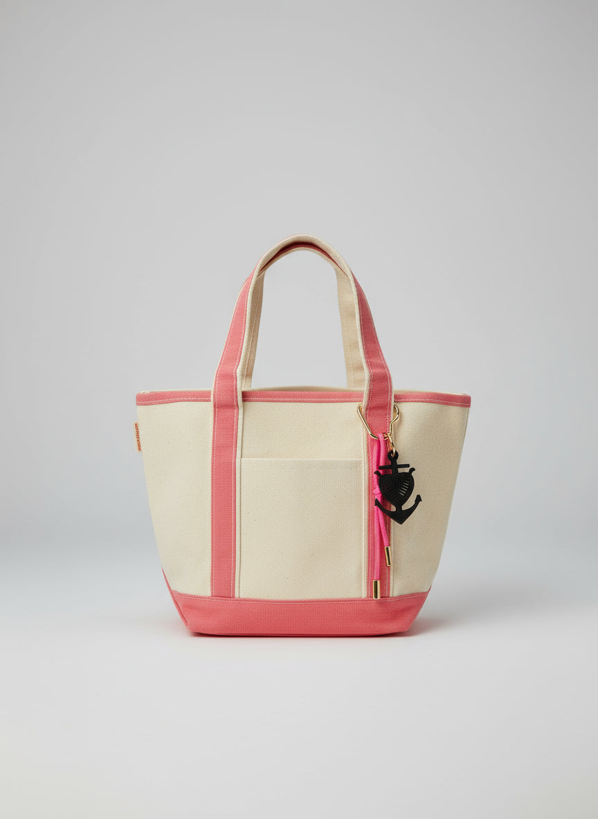 Beige and pink handbag with an anchor charm on a white surface.