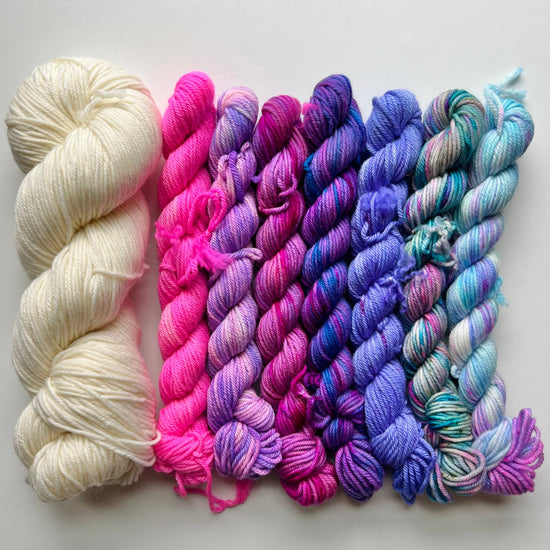 mini skeins of yarn in white, pink, and multicolor on a light gray background