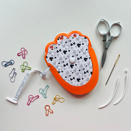 Crochet kit with scissors, needle, and pins on a light gray background