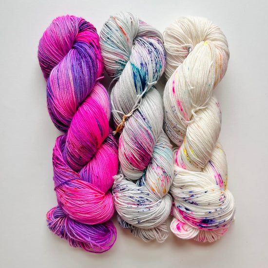 three skeins of multicolored yarn on a light gray background