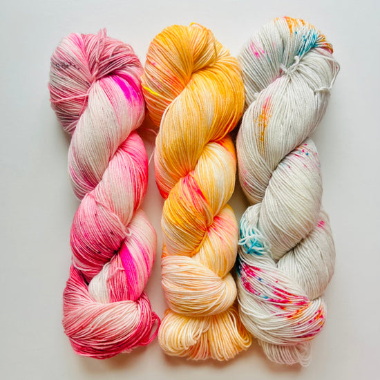Three skeins of colorful yarn on a light gray background