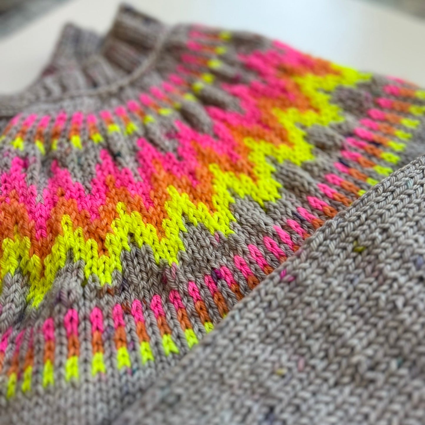 Gray sweater with colorful geometric pattern on a blurred background